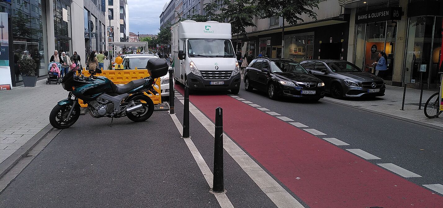 Das Bild zeigt die Fressgasse, mit einem parkenden Lieferwagen auf der Radspur
