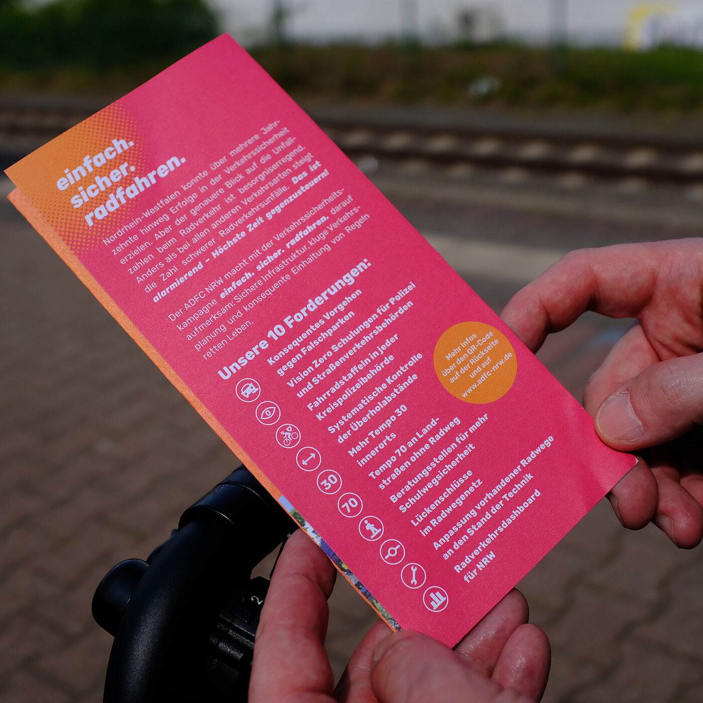 Eine Person hält einen Flyer in den Händen.